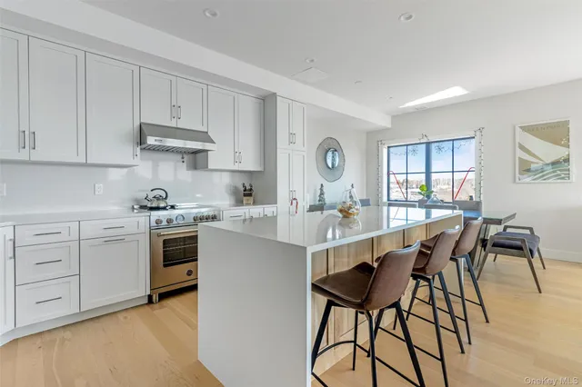 a kitchen with stainless steel appliances kitchen island granite countertop a table chairs sink and cabinets