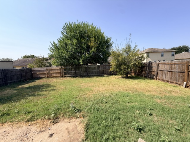 18421 Crestwind Lane Elgin, TX 78621 - Photo 34 of 34 Mature trees line the perimeter of a fully fenced backyard ready for outdoor activities.