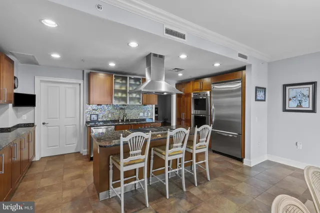 a kitchen with stainless steel appliances kitchen island granite countertop a refrigerator and microwave