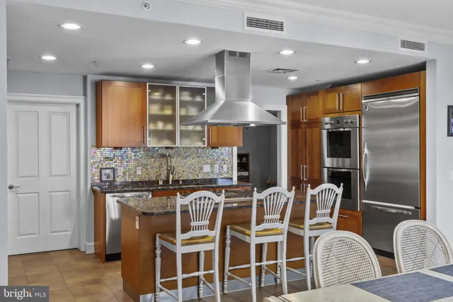 a kitchen with granite countertop kitchen island stainless steel appliances a sink and a refrigerator