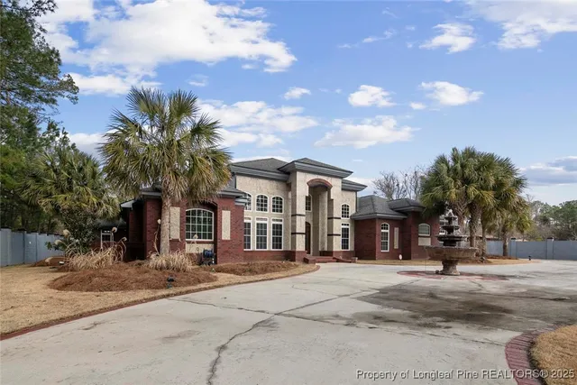 a front view of a building with a garden and trees