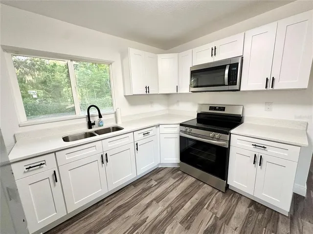 a kitchen with white cabinets appliances and a sink