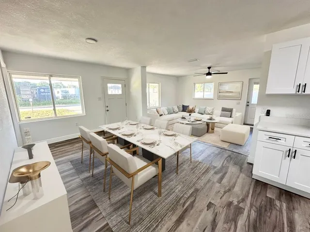 a living room with stainless steel appliances furniture a rug and a window