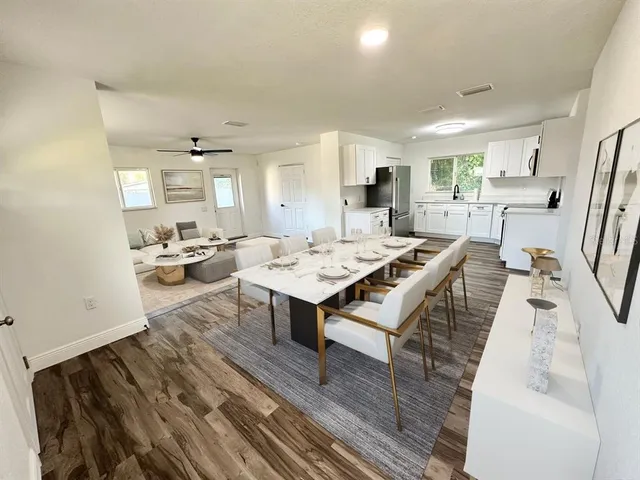 a living room with stainless steel appliances furniture a rug and a kitchen view
