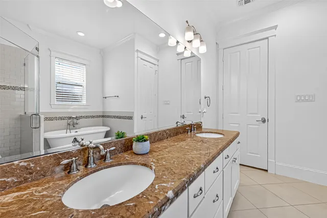 a bathroom with a granite countertop double vanity sink a mirror a bathtub and window