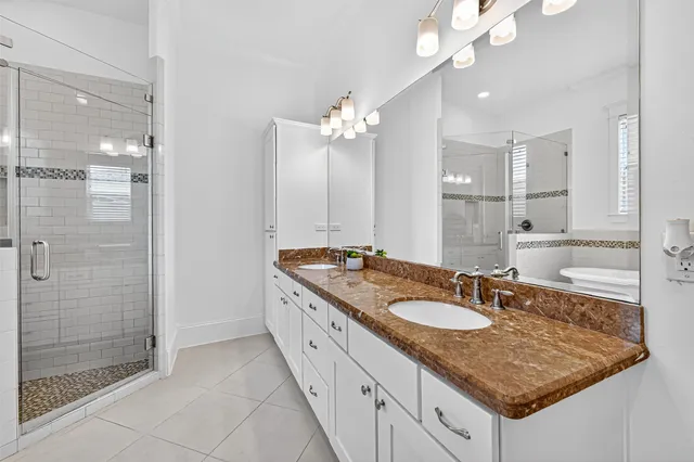 a bathroom with a granite countertop sink a mirror and a shower
