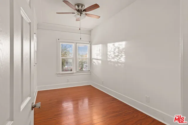 a view of empty room with wooden floor and fan