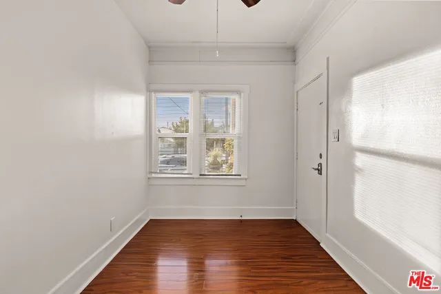 a view of an empty room with wooden floor and a window