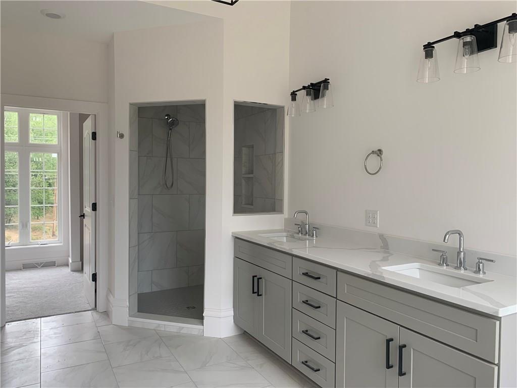 295 Hutchman Road Mars, PA 16046 - Photo 17 of 25 Large ceramic walk in shower in master bath with glass door and glass window. Double vanity with simple matte black hardware and free standing tub (not pictured). Floor matches the shower for a clean, bright, seamless look. Quartz countertops were just installed! You need to see this in person!