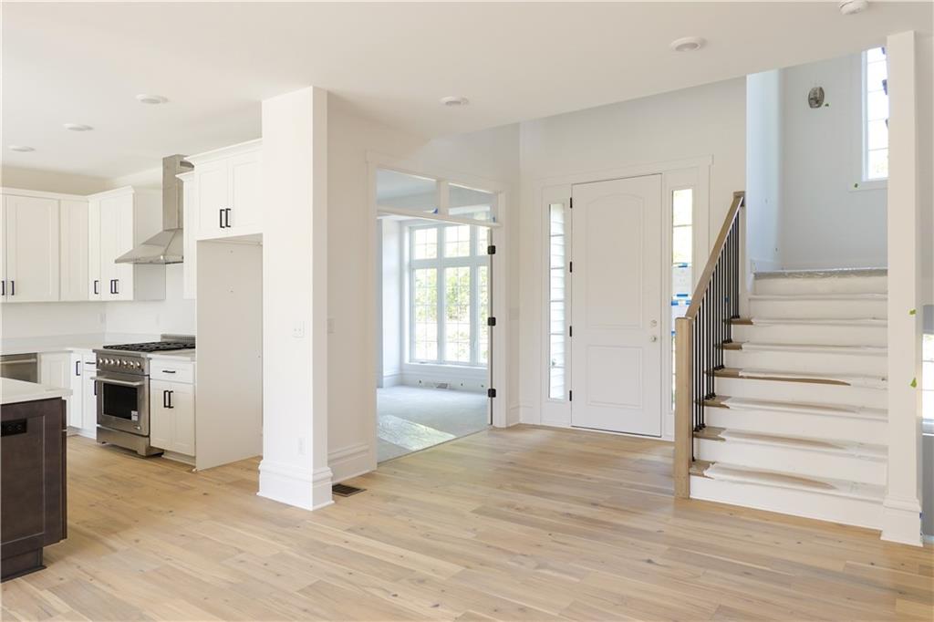 295 Hutchman Road Mars, PA 16046 - Photo 6 of 25 Two story entry and front door with side lights to allow for great natural light. Steps stained with custom color to coordinate with hardwood flooring. Simple black iron spindles create visual interest and contrast.