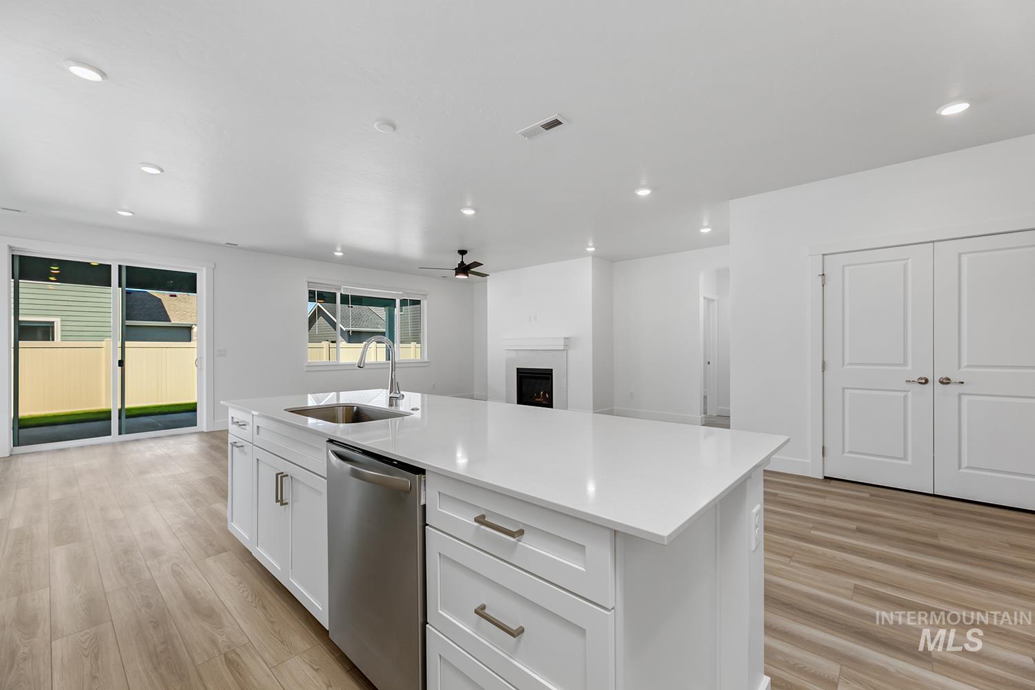 4548 West Wapoot Street Meridian, ID 83646 - Photo 11 of 17 Kitchen island with a stainless steel sink and integrated dishwasher, quartz countertop, and white cabinetry