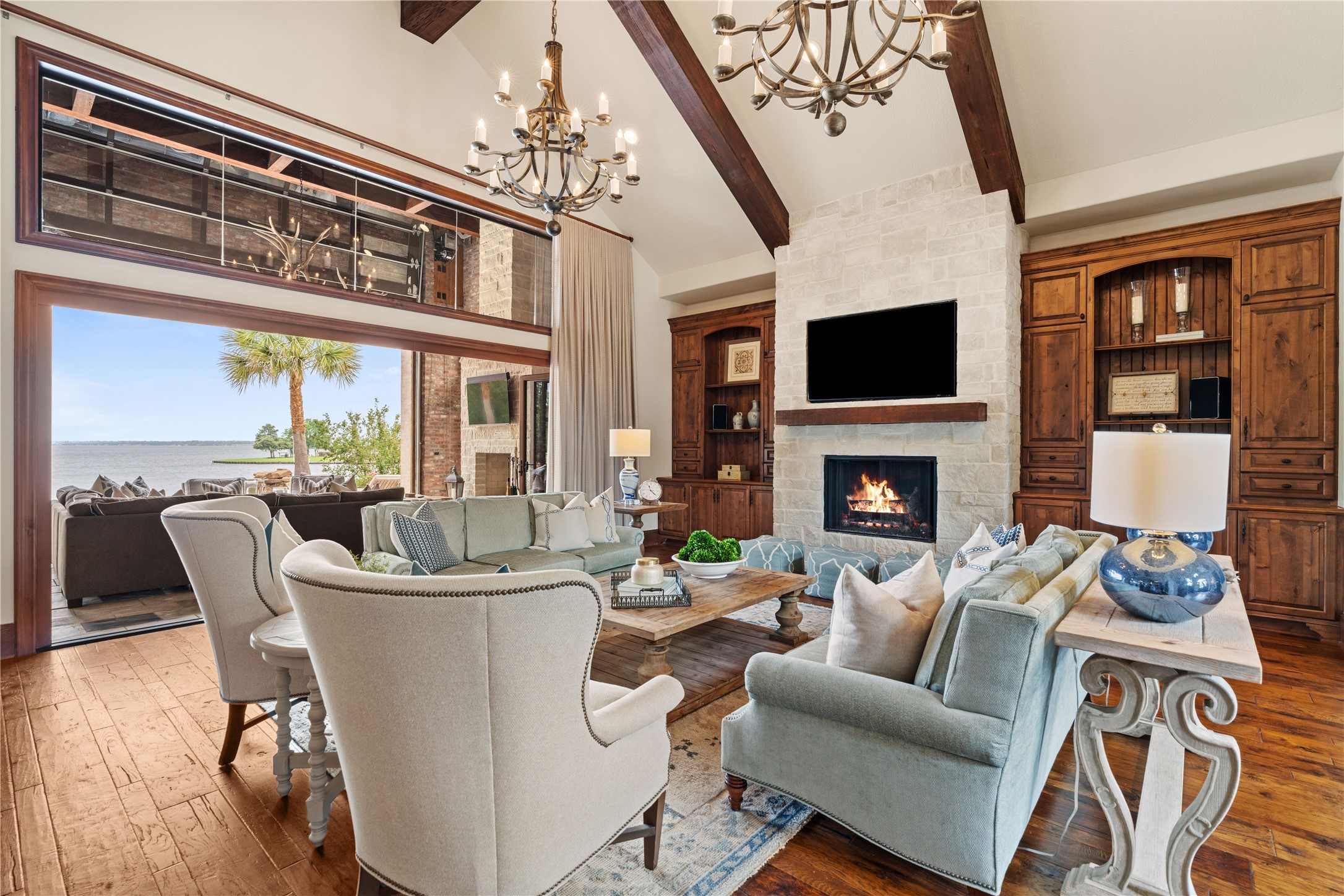12349 Longmire Trace Conroe, TX 77304 - Photo 6 of 48 Vaulted great room with exposed beams, stone fireplace, built-ins, and lake-view sliding glass doors.