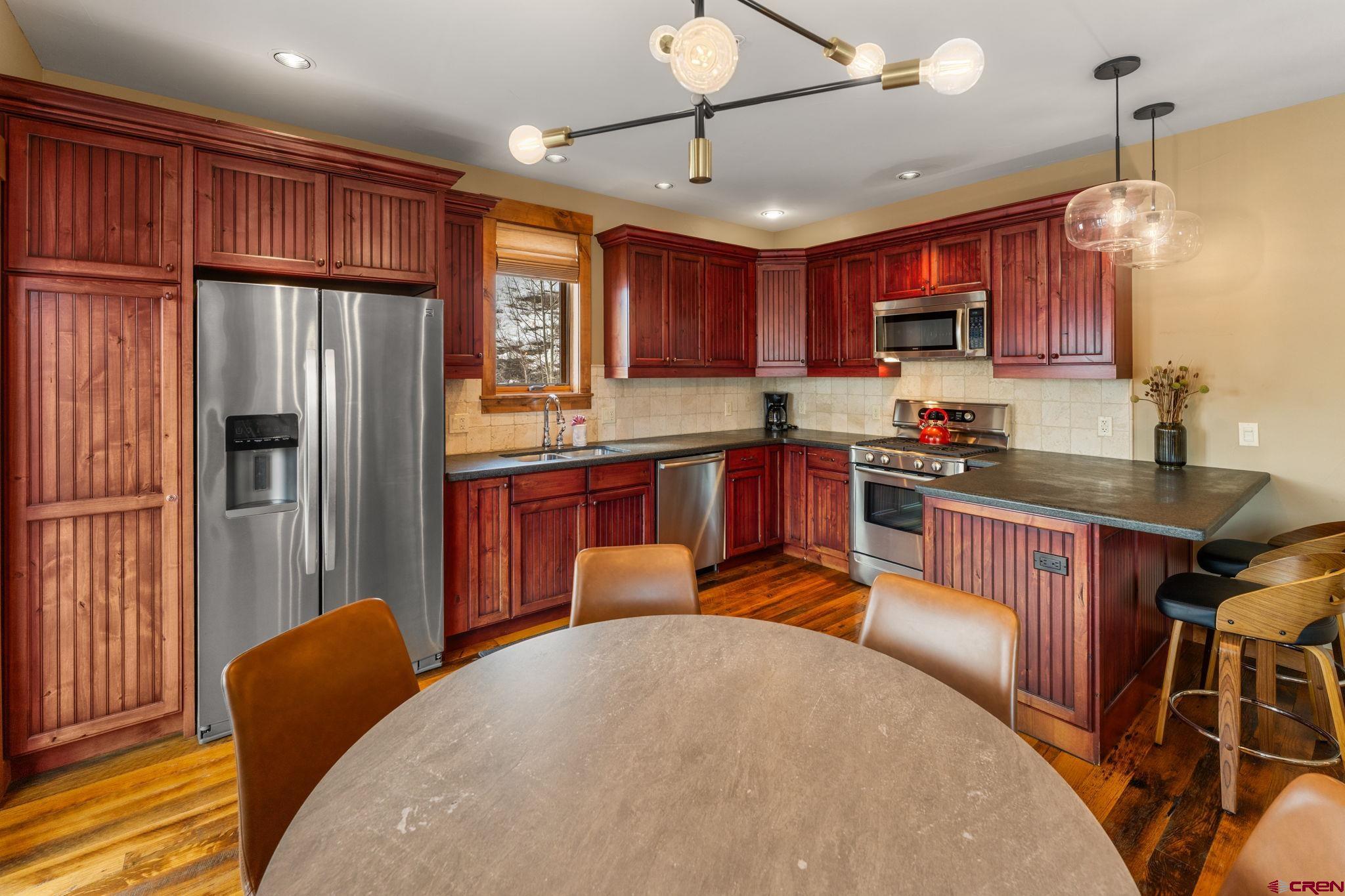 621 Gothic Road, Unit 2A Crested Butte, CO 81225 - Photo 8 of 34 a kitchen with stainless steel appliances granite countertop a refrigerator a stove top oven a sink dishwasher and wooden cabinets