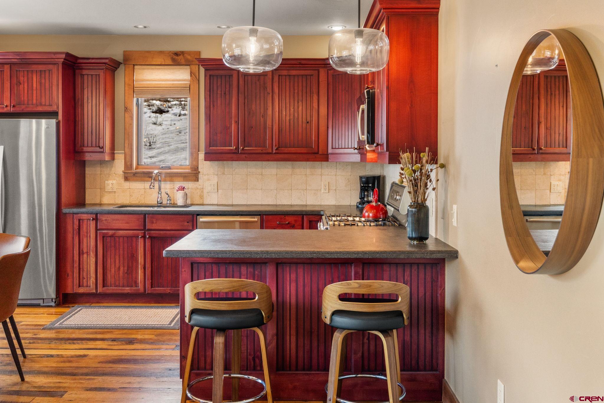 621 Gothic Road, Unit 2A Crested Butte, CO 81225 - Photo 9 of 34 a kitchen with stainless steel appliances granite countertop a table chairs and a refrigerator