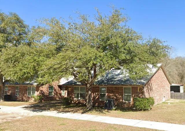 a front view of a house with a garden and tree