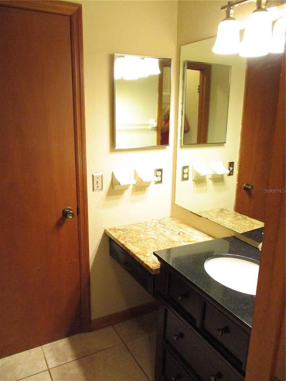 900 Southwest 62nd Boulevard, Unit D23 Gainesville, FL 32607 - Photo 17 of 37 a bathroom with a granite countertop sink and a mirror