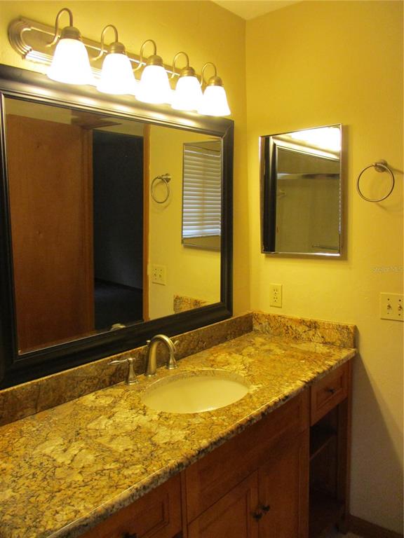 900 Southwest 62nd Boulevard, Unit D23 Gainesville, FL 32607 - Photo 18 of 37 a bathroom with a granite countertop sink and a mirror