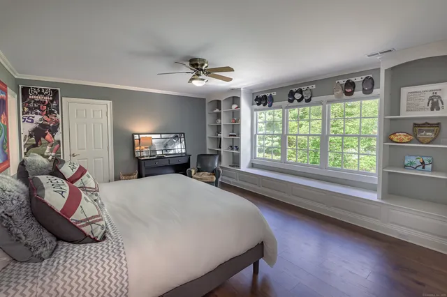 a spacious bedroom with a bed a dresser and a chandelier
