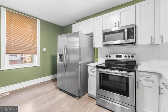 a kitchen with white cabinets stainless steel appliances and a window