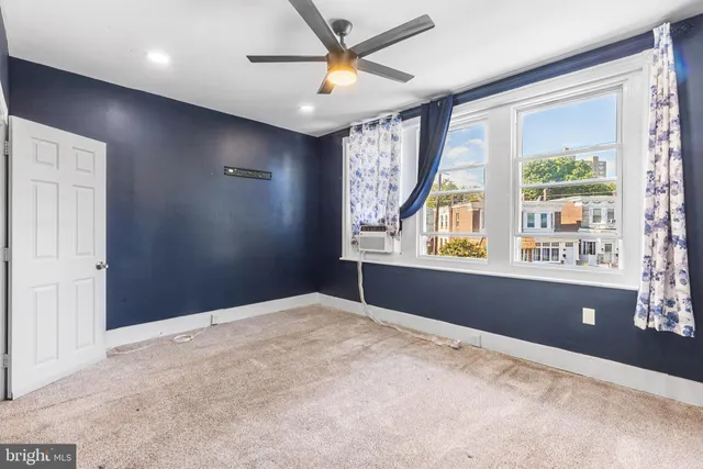 an empty room with windows and fan