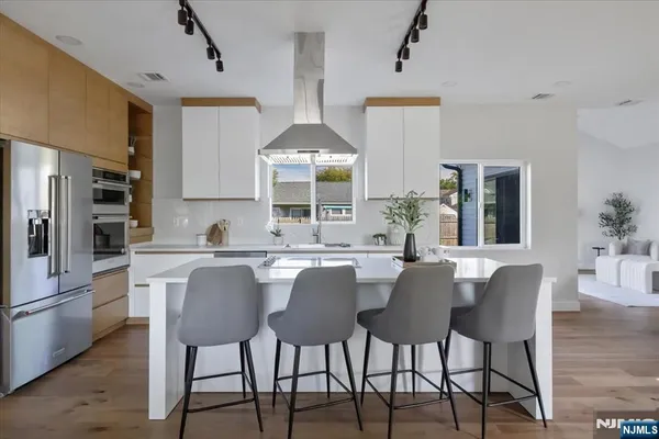 a kitchen with stainless steel appliances kitchen island granite countertop a table chairs and a white cabinets