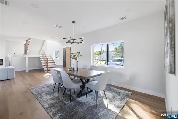 a dining room with wooden floor a chandelier a wooden table and chairs