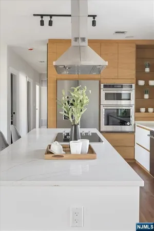 a kitchen with stainless steel appliances kitchen island granite countertop a table chairs sink and cabinets
