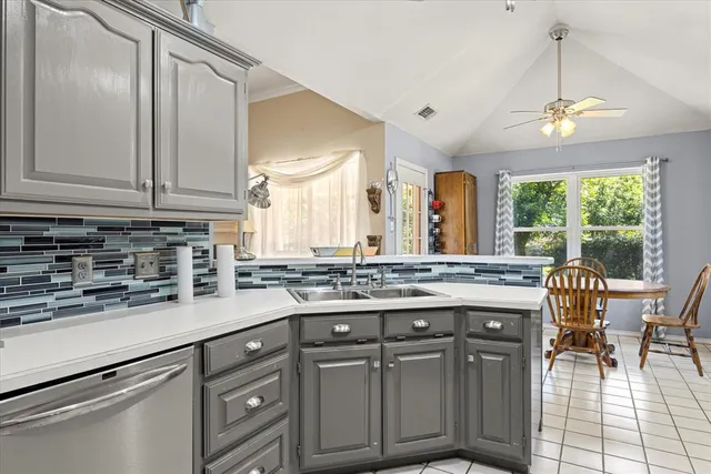 a kitchen with stainless steel appliances granite countertop a stove a sink dishwasher and white cabinets with wooden floor