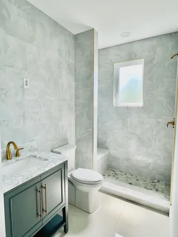 a bathroom with a granite countertop sink a toilet and shower
