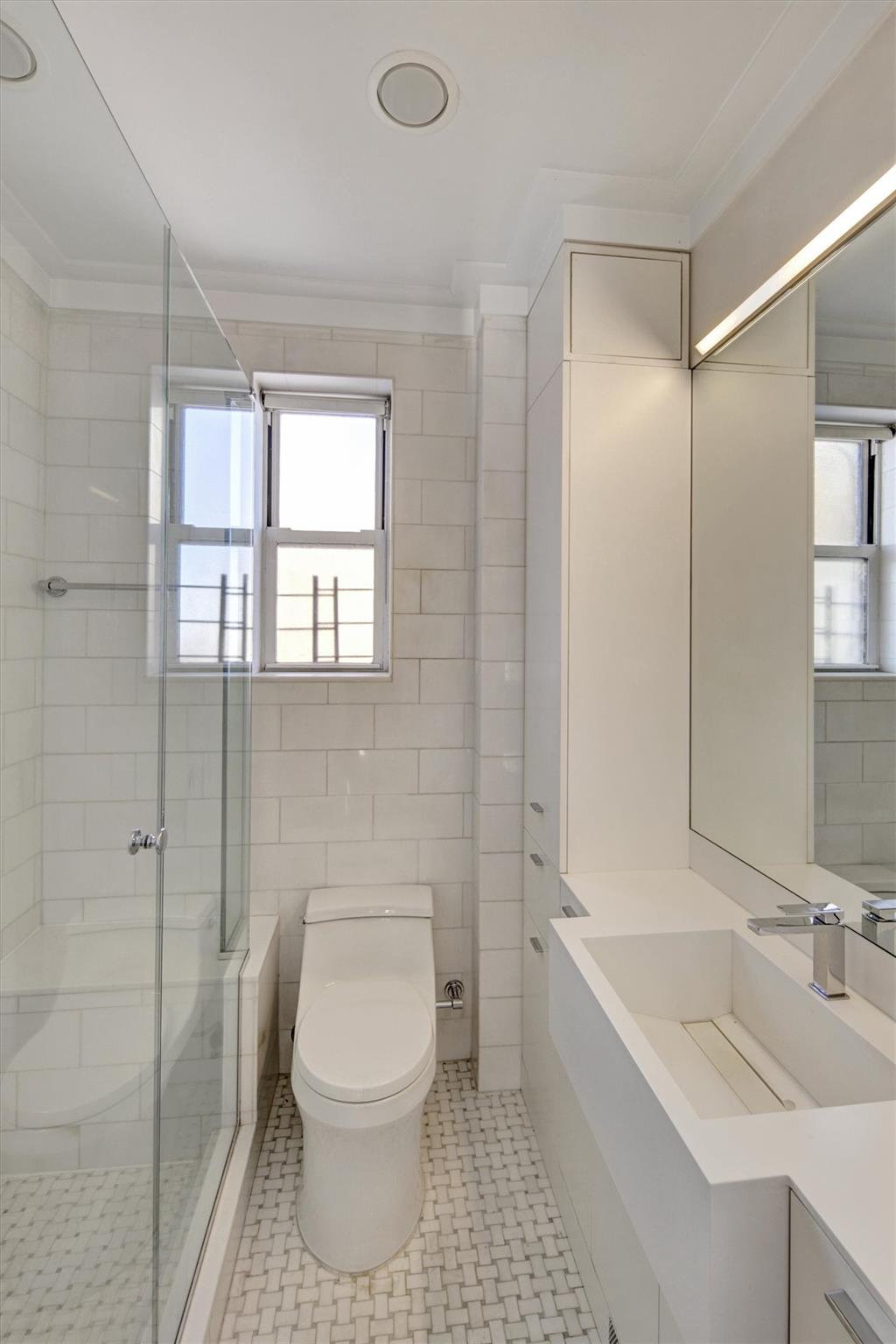 65 East 96th Street, Unit 16B Manhattan, NY 10128 - Photo 26 of 45 Bathroom featuring a shower with shower door, tile walls, vanity, toilet, and crown molding