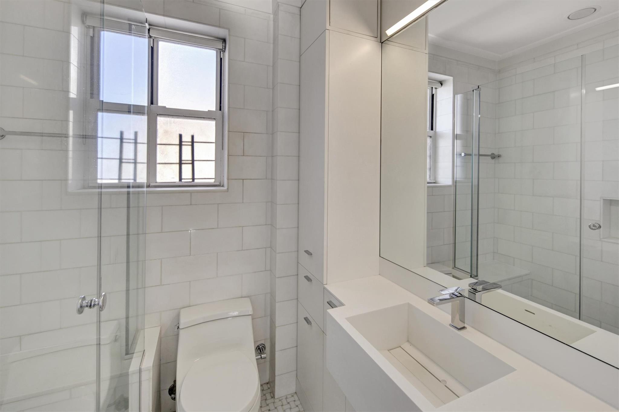 65 East 96th Street, Unit 16B Manhattan, NY 10128 - Photo 28 of 45 Bathroom featuring walk in shower, vanity, toilet, and tile walls