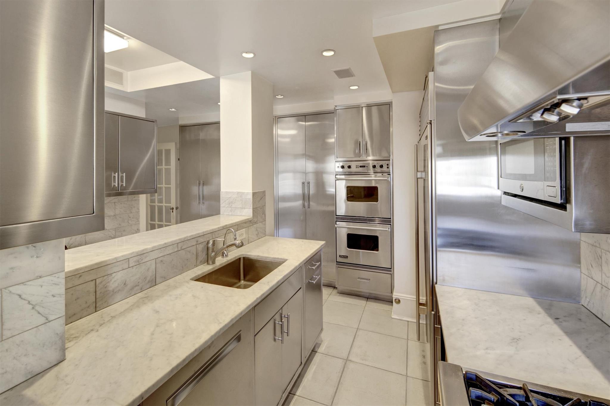 65 East 96th Street, Unit 16B Manhattan, NY 10128 - Photo 37 of 45 Kitchen featuring sink, island range hood, double oven, light stone countertops, and backsplash