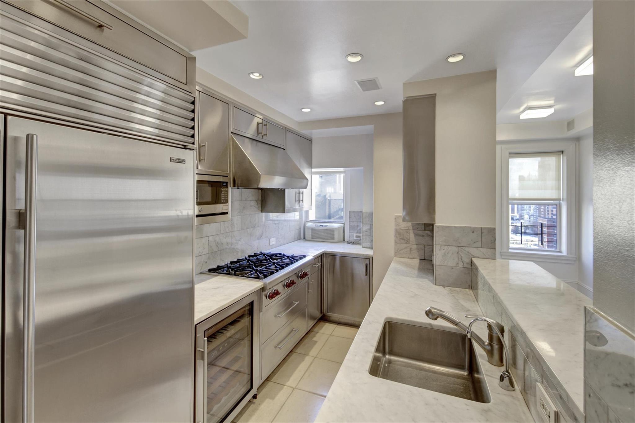 65 East 96th Street, Unit 16B Manhattan, NY 10128 - Photo 39 of 45 Kitchen featuring wine cooler, sink, light tile patterned floors, appliances with stainless steel finishes, and light stone countertops