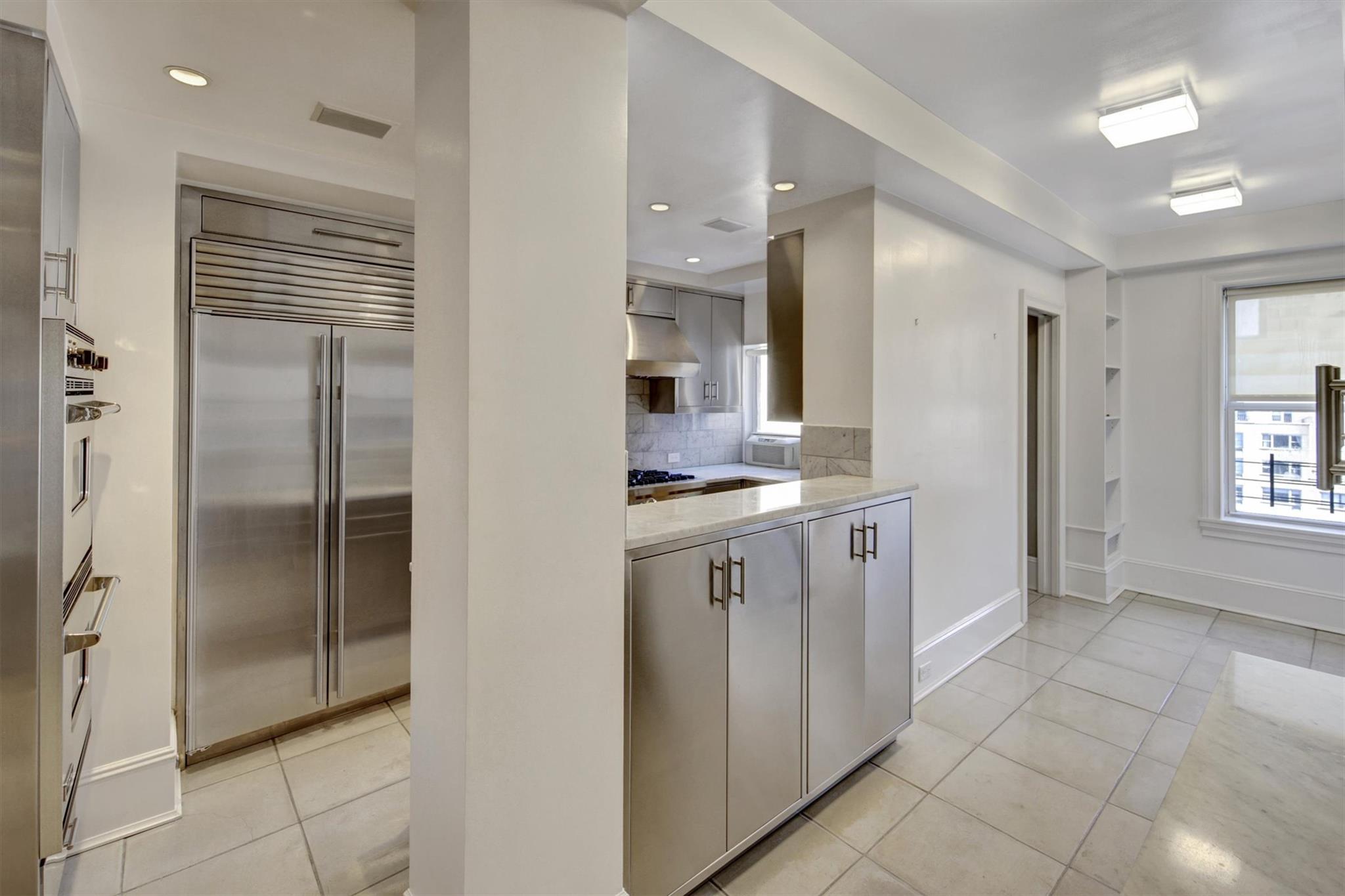 65 East 96th Street, Unit 16B Manhattan, NY 10128 - Photo 43 of 45 Kitchen featuring light tile patterned floors, appliances with stainless steel finishes, range hood, light stone counters, and decorative backsplash
