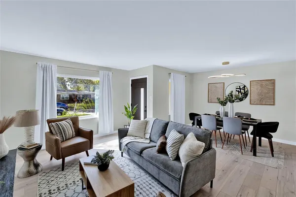 a living room with furniture potted plant and open kitchen view