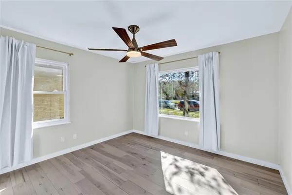 a view of empty room with wooden floor and fan