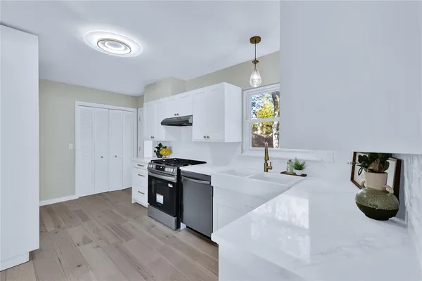 a kitchen with stainless steel appliances granite countertop a stove and a wooden floors