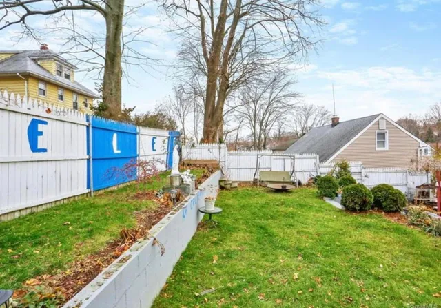 a view of a house with a small yard and a large tree