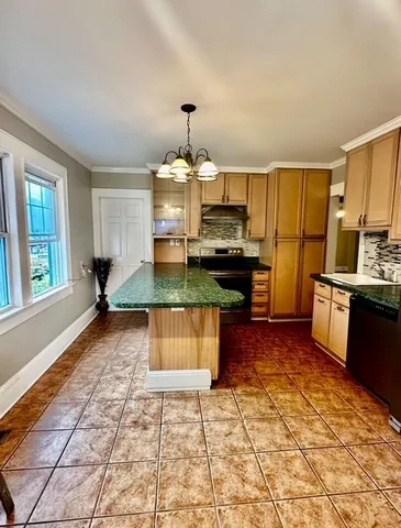 a large kitchen with kitchen island granite countertop a stove a sink a counter top space and cabinets