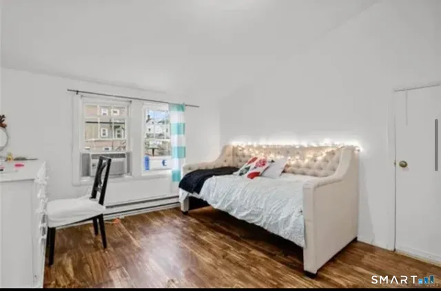 a bedroom with a bed wooden floor and window