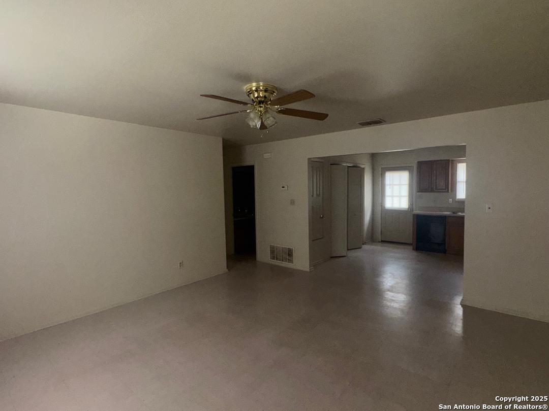 823 Dallas Street Pleasanton, TX 78064 - Photo 2 of 7 an empty room with chandelier fan and windows