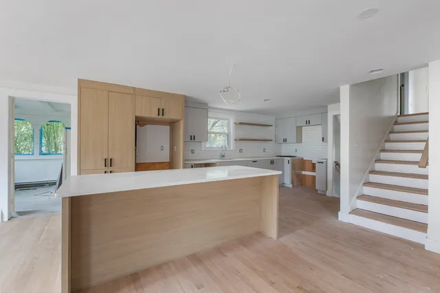 a large white kitchen with wooden floors and a fireplace