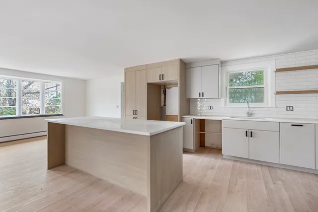 a large kitchen with a stove a sink dishwasher a refrigerator and white cabinets with wooden floor