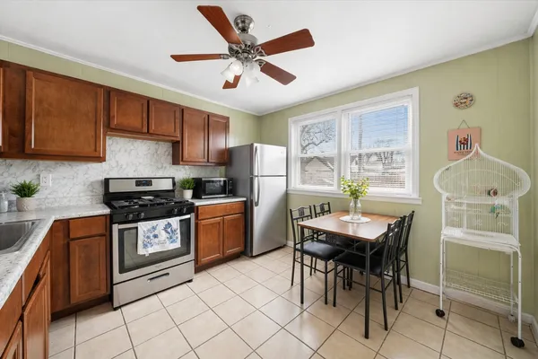 a kitchen with stainless steel appliances granite countertop a stove a refrigerator a sink a dining table and chairs with wooden floor