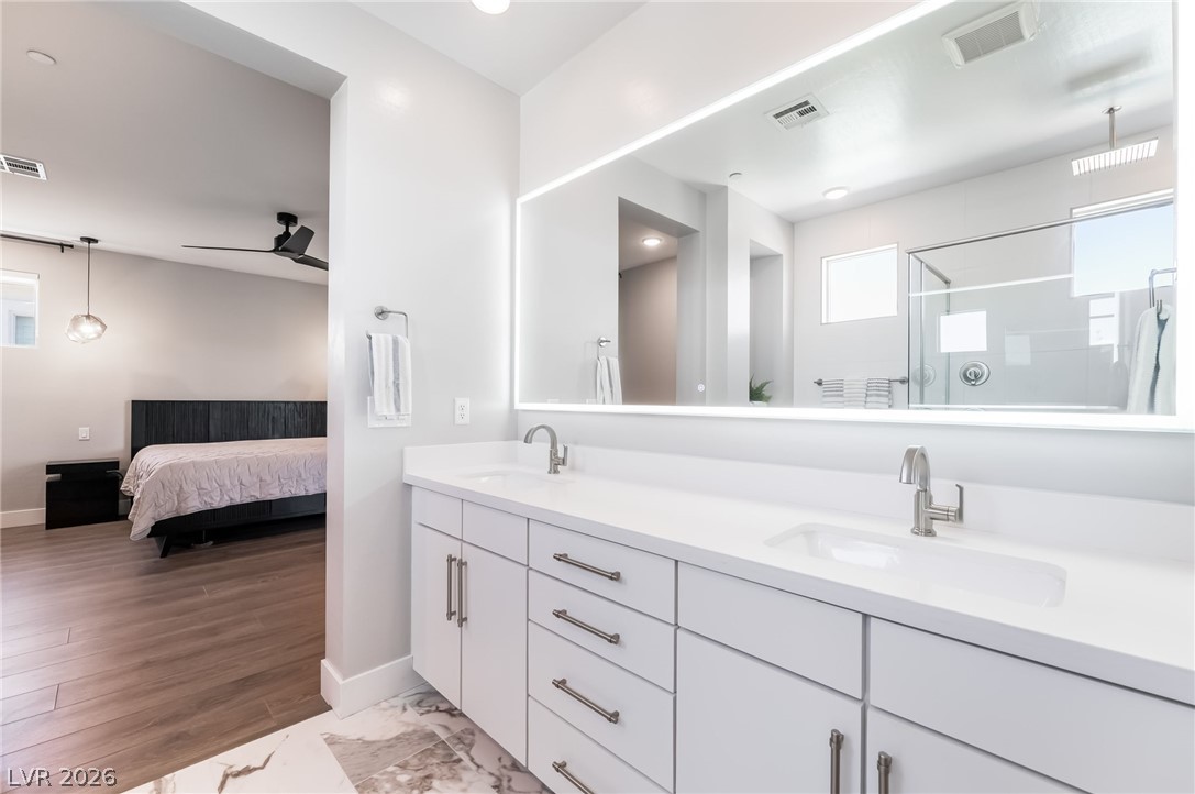 2166 Trivero Street Henderson, NV 89044 - Photo 28 of 61 A well-lit primary bathroom vanity provides abundant storage and dual sinks, reflecting the adjacent sleeping quarters.