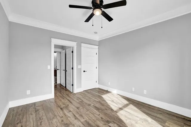 a view of empty room with wooden floor and ceiling fan