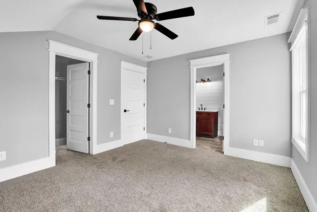 an empty room with closet and a ceiling fan