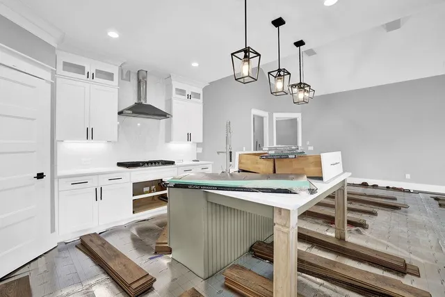 a kitchen with stainless steel appliances granite countertop a stove a sink dishwasher a refrigerator white cabinets and wooden floor