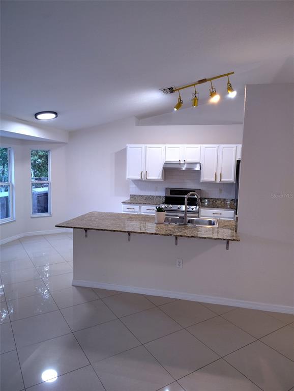 153 Rosedale Avenue Spring Hill, FL 34606 - Photo 5 of 16 a kitchen with granite countertop a stove and cabinets