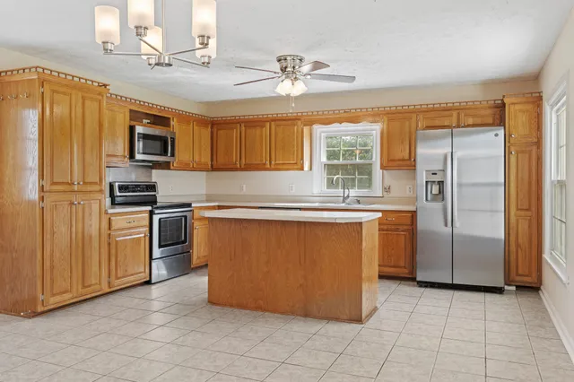 an empty room with a chandelier fan and windows